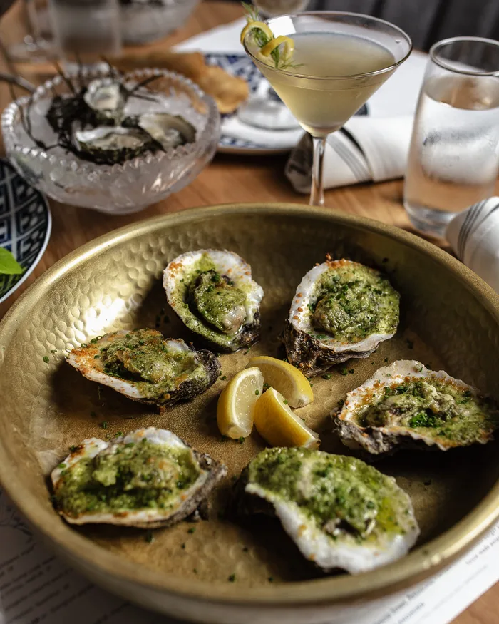 Chargrilled oysters with lemon on a brass platter at Pearl & Horn